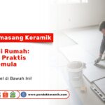 Seorang pria sedang berlutut memasang ubin lantai abu-abu menggunakan alat pengukur sebagai visual cara memasang keramik sendiri di rumah: panduan praktis untuk pemula