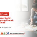 Seorang wanita sedang menggunakan kuas kecil untuk mengoleskan cat emas pada retakan ubin sebagai visual teknik kintsugi: seni memperbaiki keramik yang pecah dengan emas